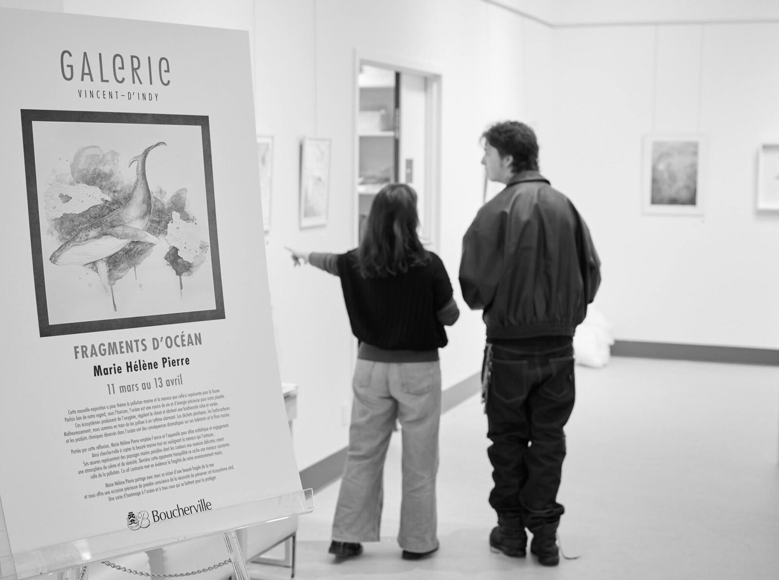 Deux personnes visitent l’exposition Fragments d’océan à la Galerie Vincent-d’Indy, près de son affiche.